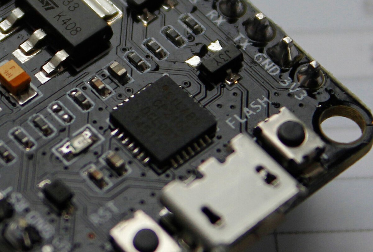 Detalhe macro de placa NodeMCU mostrando o chip CP2102 em encapsulamento QFN ao lado do conector micro-USB