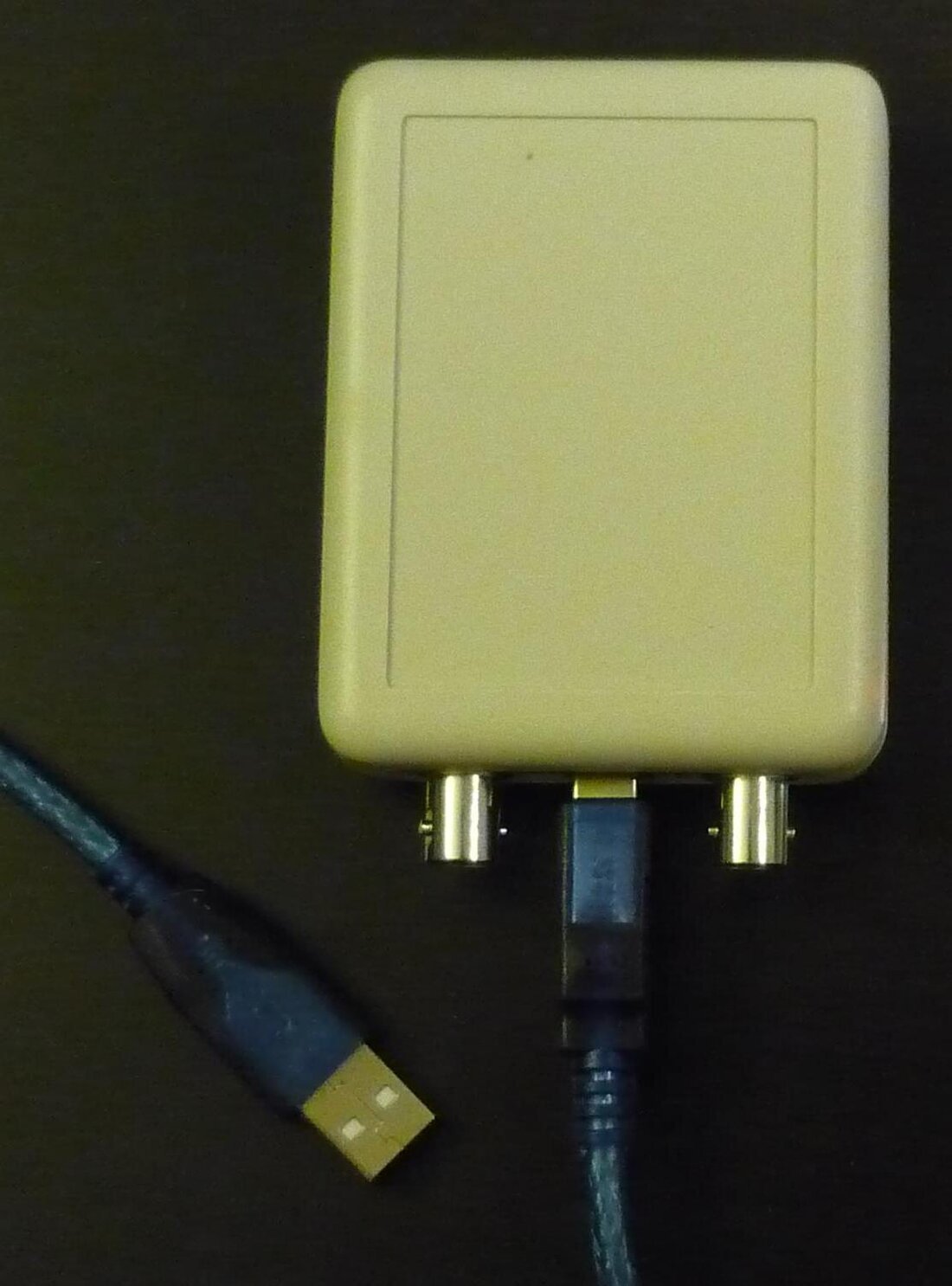 Osciloscópio USB de dois canais: caixa retangular com dois conectores BNC na borda e um cabo USB