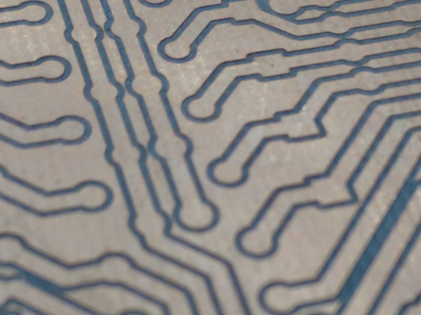 Macrofotografia de uma placa de circuito impresso fresada, com os sulcos de isolação entre as trilhas de cobre