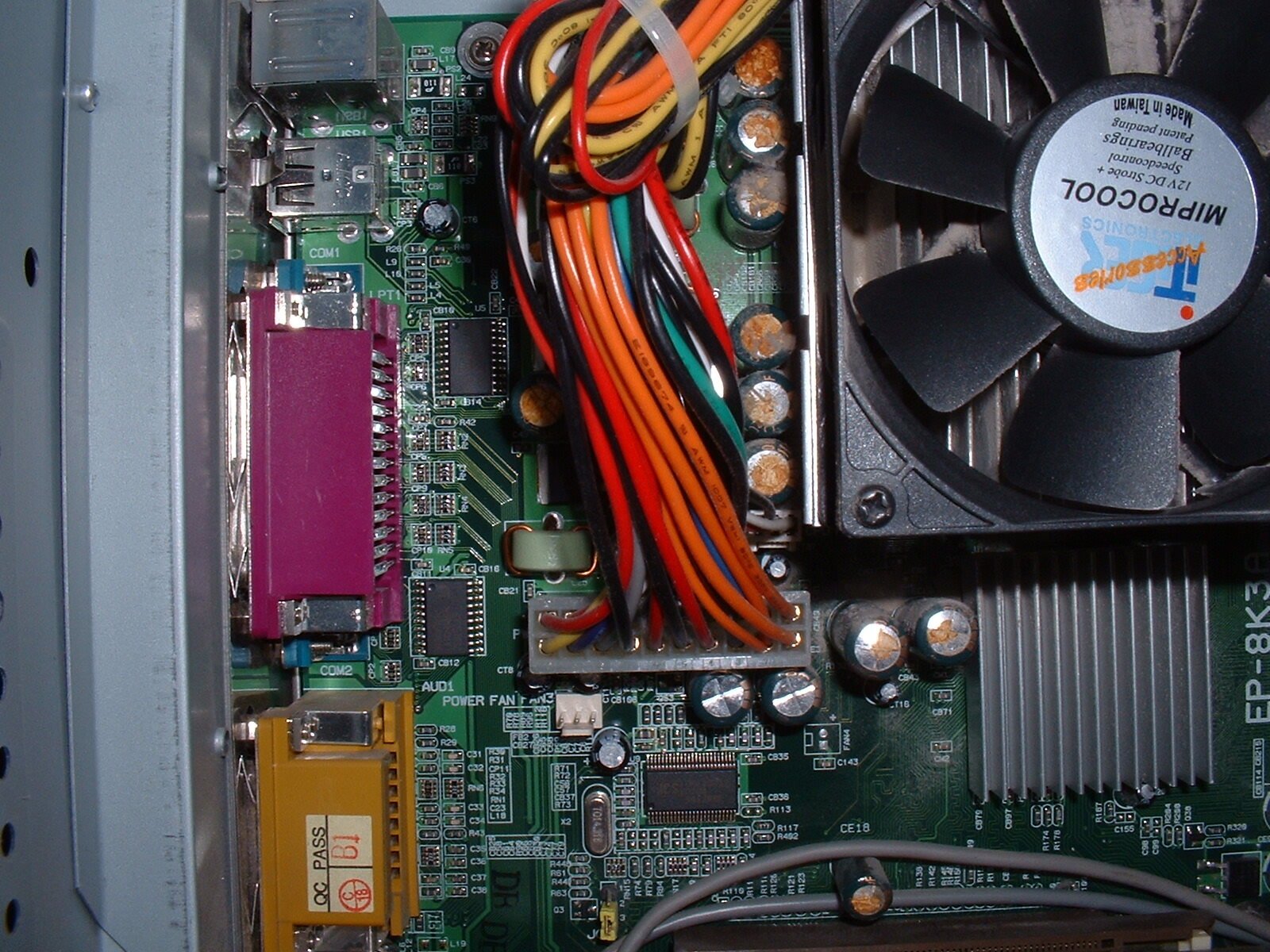 Placa-mãe de computador com vários capacitores eletrolíticos estufados e com vazamento marrom no topo, agrupados ao redor do dissipador do processador
