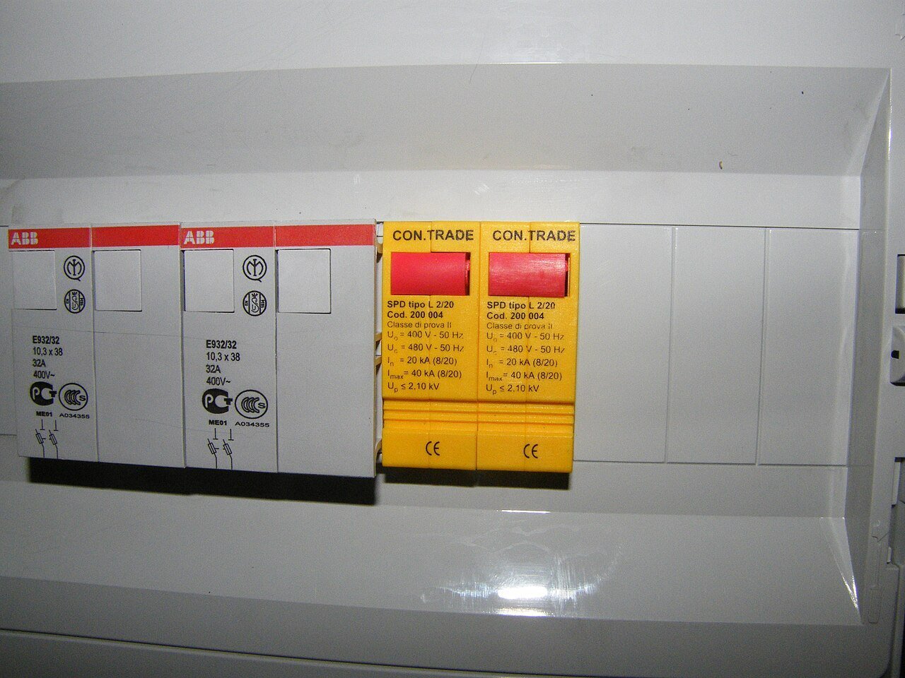 Quadro de distribuição com dois porta-fusíveis brancos e dois DPS amarelos de trilho DIN, com as especificações In 20 kA, Imax 40 kA e Up 2,10 kV impressas na frente