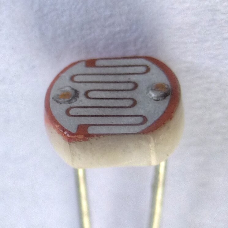 Close de um fotorresistor de sulfeto de cádmio, com a trilha em zigue-zague sobre a pastilha cerâmica