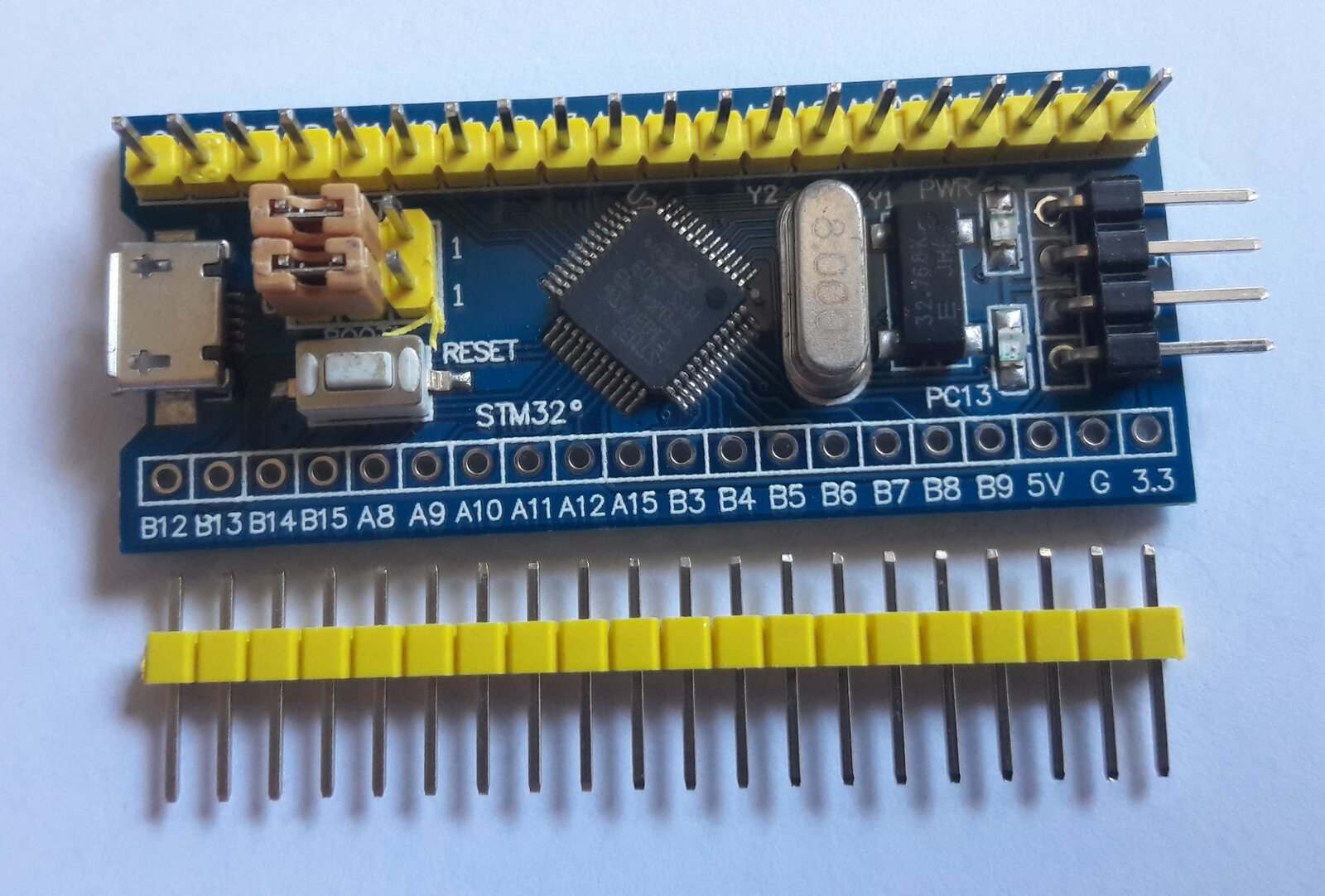 Placa azul com microcontrolador STM32F103C8T6 mostrando, à direita, o conector de quatro pinos usado para depuração por SWD